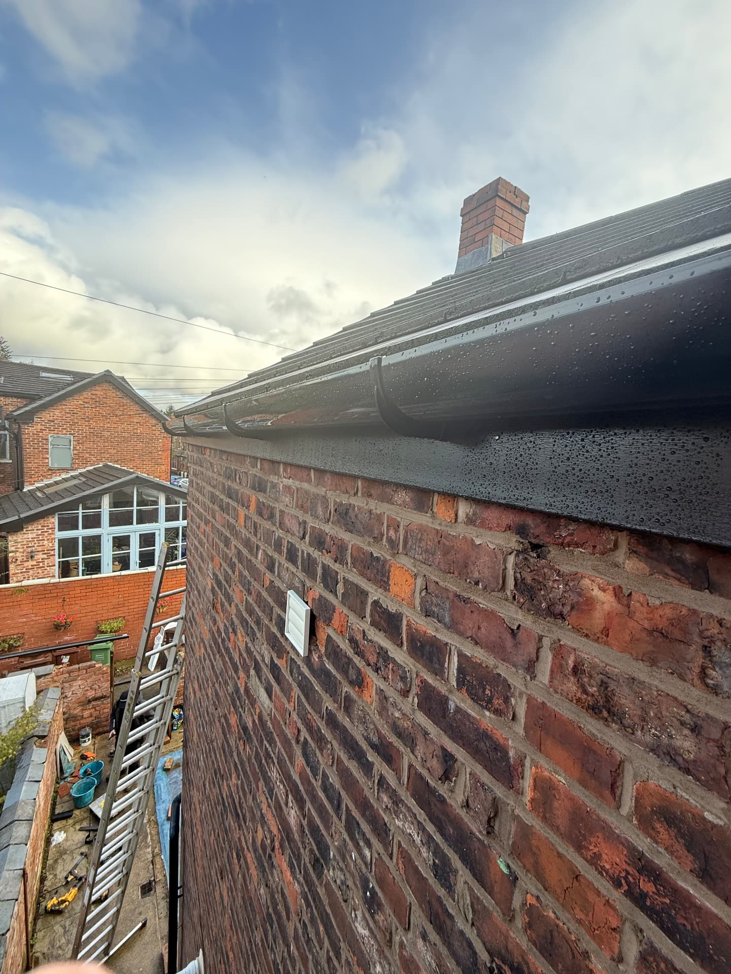 Close-up of black guttering and fascia along a brick home roofline