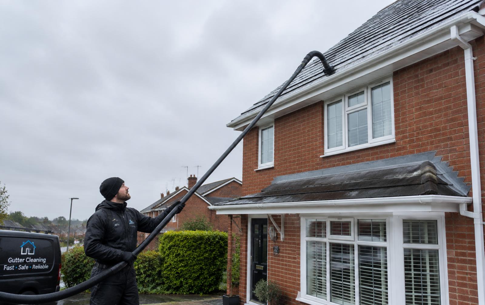 Gutter cleaner using a gutter vacuum on a brick house